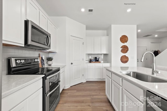 kitchen featuring white cabinetry, appliances with stainless steel finishes, sink, and light hardwood / wood-style flooring