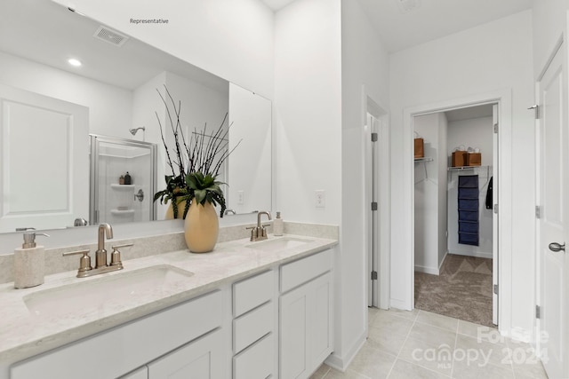 bathroom with a shower with door, vanity, and tile patterned flooring