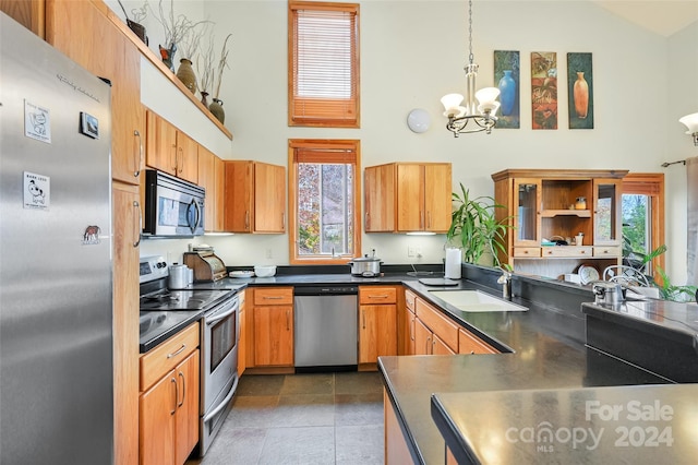 kitchen featuring stainless steel appliances, sink, dark tile patterned floors, a chandelier, and pendant lighting