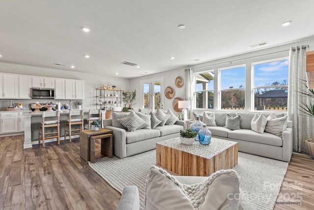 living room with wood finished floors, visible vents, and recessed lighting