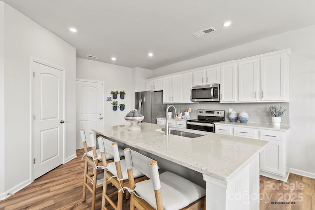 kitchen with light wood finished floors, visible vents, appliances with stainless steel finishes, and a sink