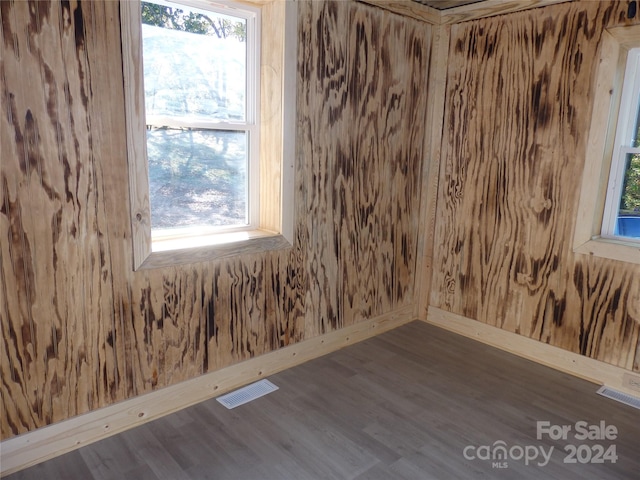 empty room featuring wooden walls and dark hardwood / wood-style floors