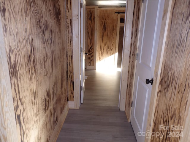 hall with light hardwood / wood-style floors and wood walls