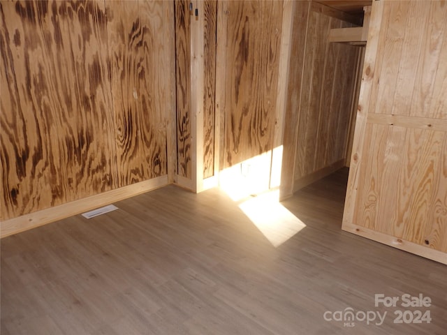 unfurnished room featuring wood walls and hardwood / wood-style flooring