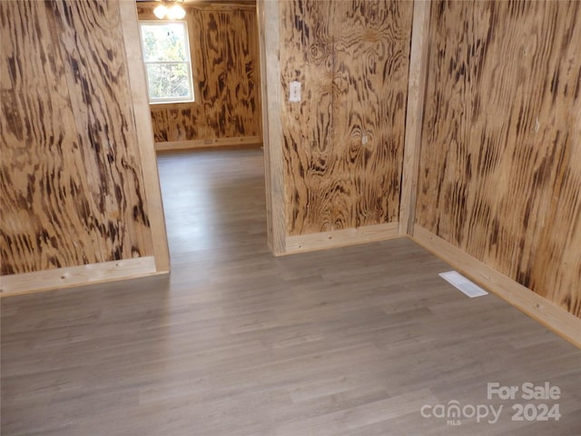 spare room featuring wood walls and wood-type flooring