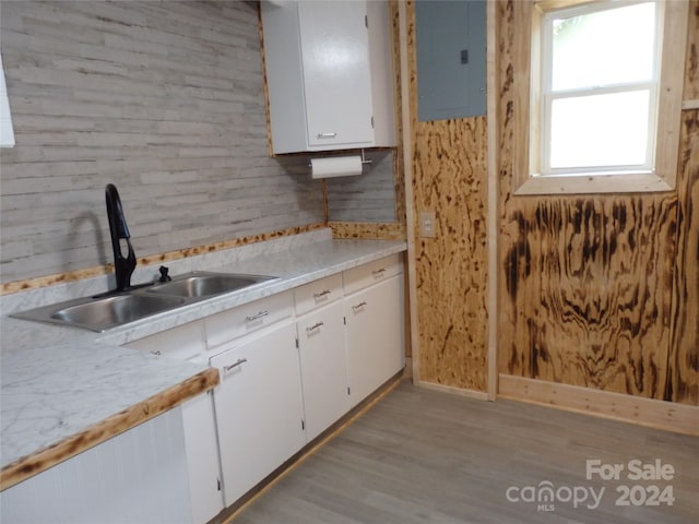 kitchen with sink, electric panel, light wood-type flooring, and white cabinets