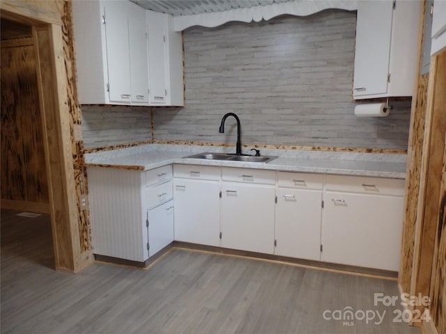 kitchen featuring light hardwood / wood-style flooring, tasteful backsplash, sink, and white cabinets