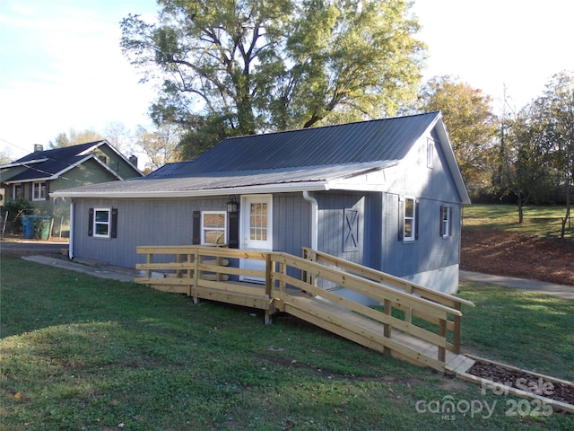 exterior space featuring metal roof, a deck, and a front lawn