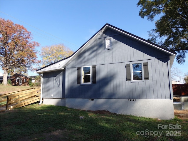 view of side of home featuring a yard, fence, and crawl space