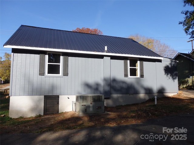 view of property exterior featuring central AC unit, metal roof, and crawl space
