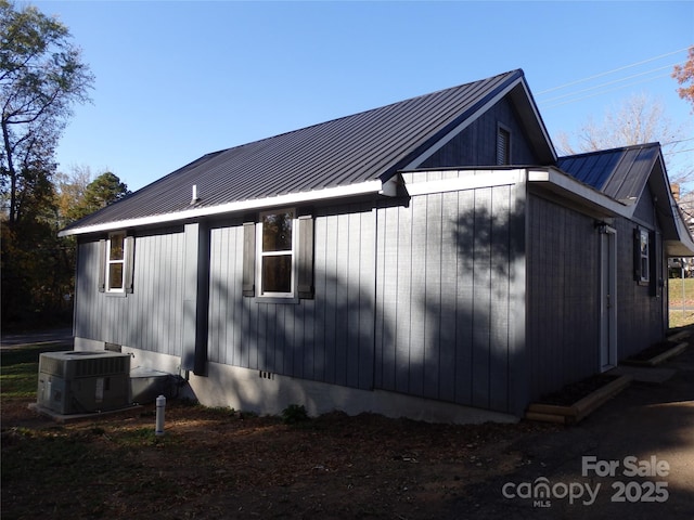 view of side of home with cooling unit, metal roof, and a standing seam roof
