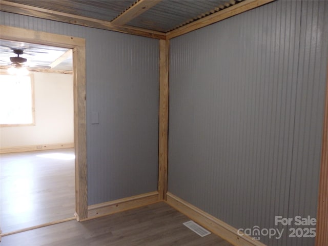 unfurnished room with wood finished floors, baseboards, a ceiling fan, and visible vents