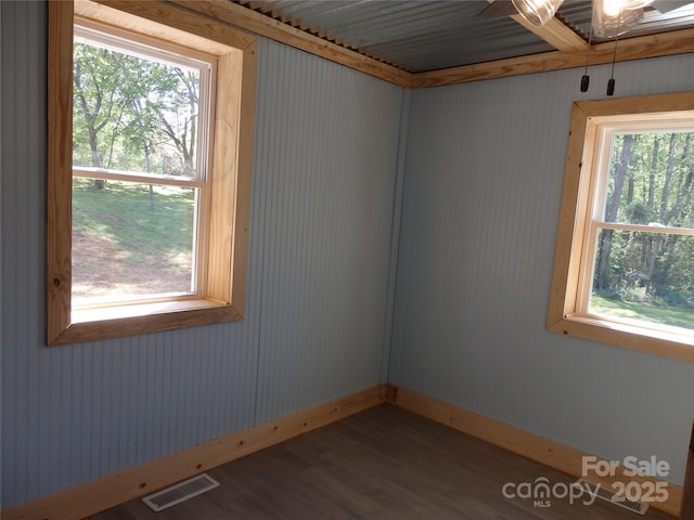 empty room featuring visible vents, baseboards, and wood finished floors