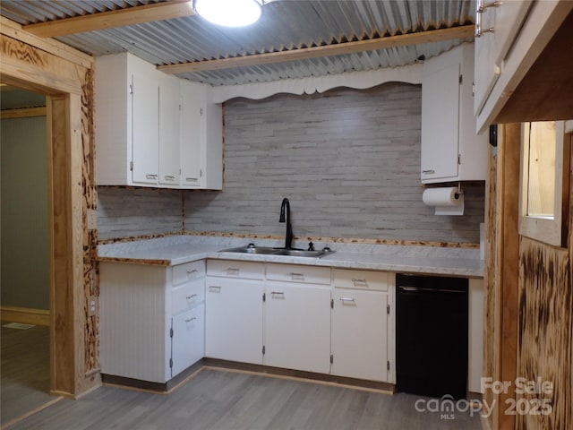 kitchen featuring a sink, light countertops, light wood finished floors, white cabinetry, and backsplash