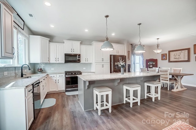 kitchen with sink, stainless steel appliances, a kitchen island, plenty of natural light, and white cabinets