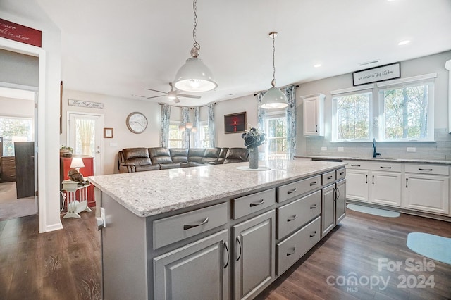 kitchen with white cabinets, dark hardwood / wood-style flooring, a kitchen island, and a wealth of natural light