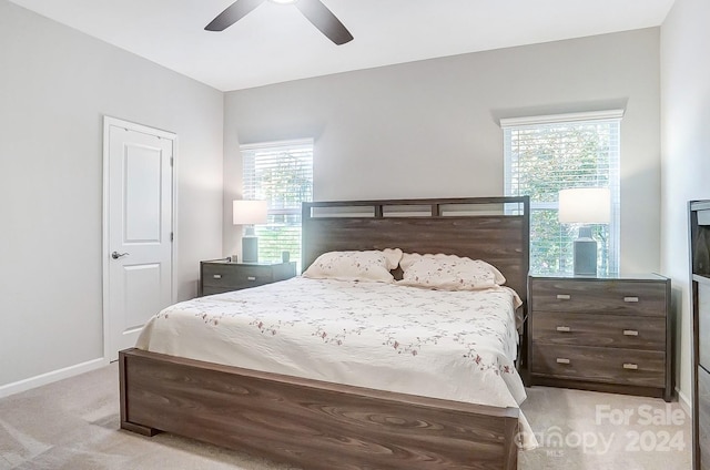 bedroom with ceiling fan, light carpet, and multiple windows