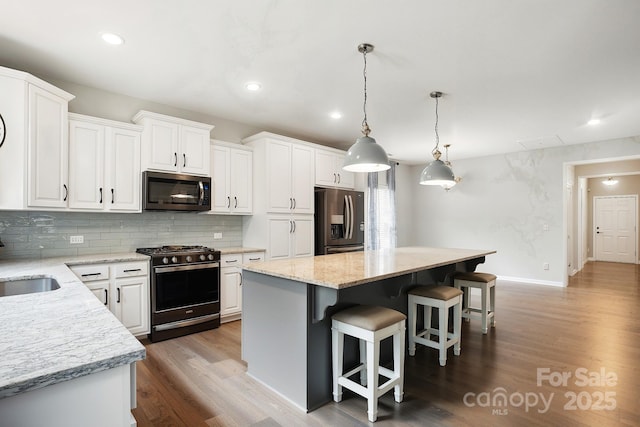 25622 Seagull Dr Unit 645, Lancaster, SC 29720 - kitchen with stainless steel appliances, decorative backsplash, a kitchen island, wood finished floors, and a kitchen bar
