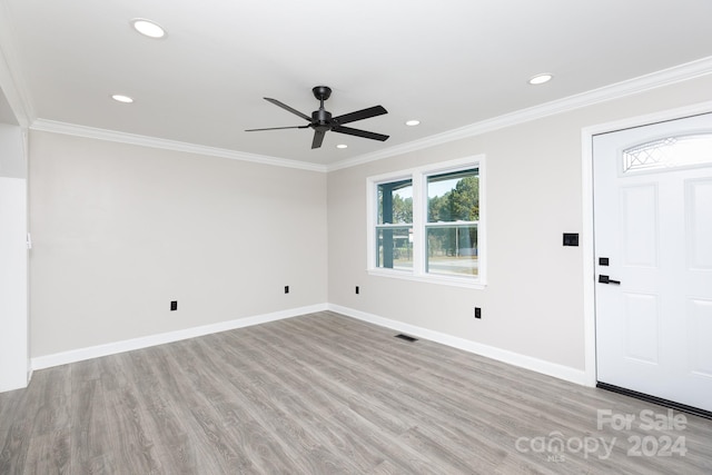 spare room featuring light wood-type flooring, ceiling fan, and crown molding