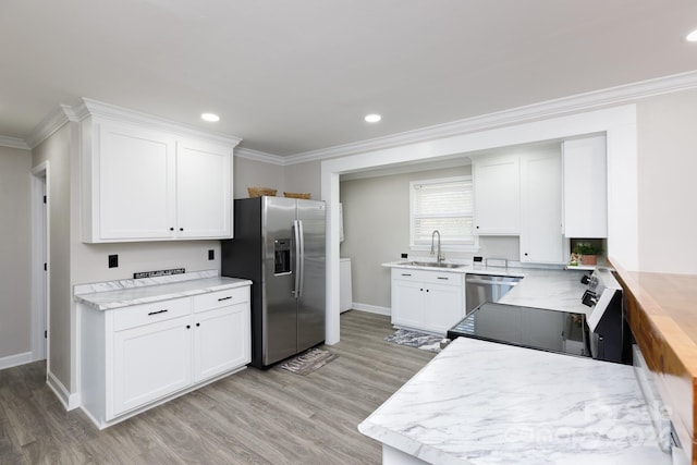 kitchen with stainless steel appliances, white cabinetry, sink, and light hardwood / wood-style flooring