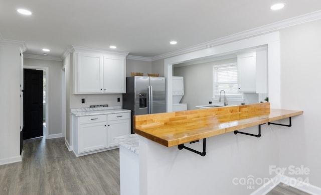 kitchen featuring white cabinetry, stainless steel refrigerator with ice dispenser, light hardwood / wood-style flooring, crown molding, and butcher block countertops