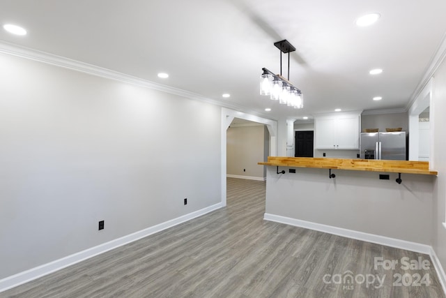 kitchen featuring butcher block counters, stainless steel refrigerator with ice dispenser, a kitchen bar, and kitchen peninsula