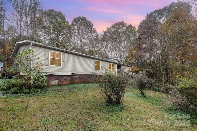 property exterior at dusk featuring a lawn