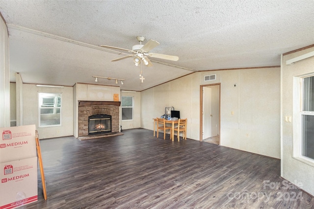 unfurnished living room featuring dark wood-type flooring, a stone fireplace, a textured ceiling, and lofted ceiling