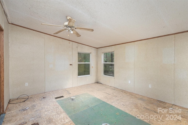 empty room featuring ceiling fan, a textured ceiling, vaulted ceiling, and crown molding