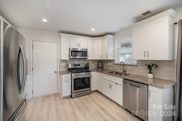 kitchen featuring stainless steel appliances, light hardwood / wood-style floors, white cabinets, and sink