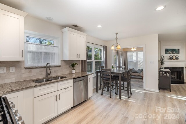 kitchen featuring stainless steel dishwasher, white cabinets, plenty of natural light, and sink