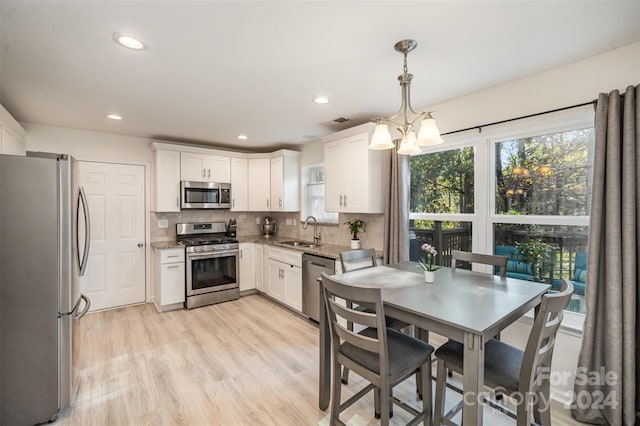 kitchen with pendant lighting, stainless steel appliances, white cabinetry, and sink