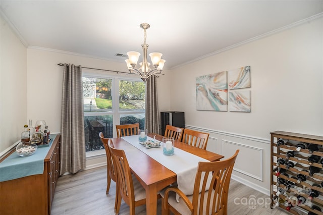 dining area featuring light wood-type flooring, a chandelier, and crown molding