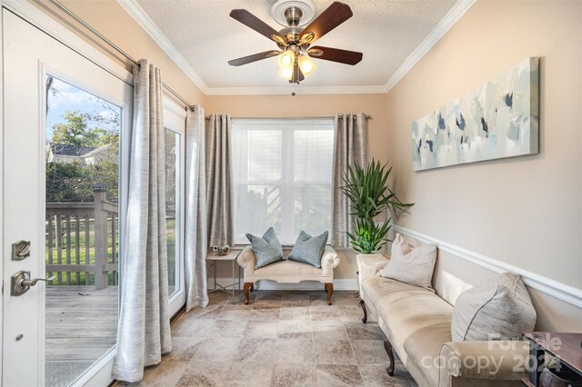 living area with a textured ceiling, ceiling fan, and crown molding