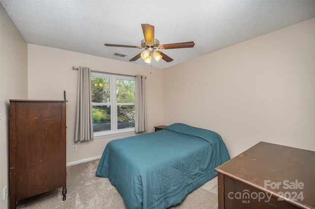 carpeted bedroom with ceiling fan and a textured ceiling