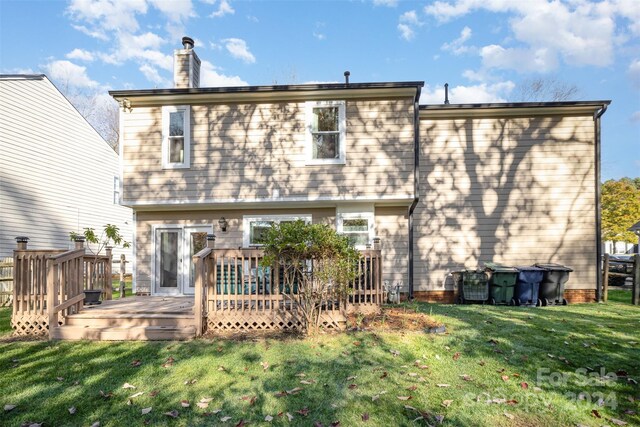 rear view of property with a wooden deck and a yard