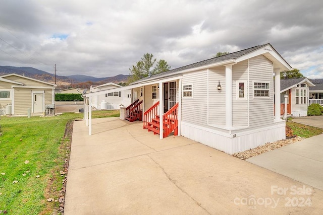 manufactured / mobile home with an outbuilding, a front lawn, and a mountain view