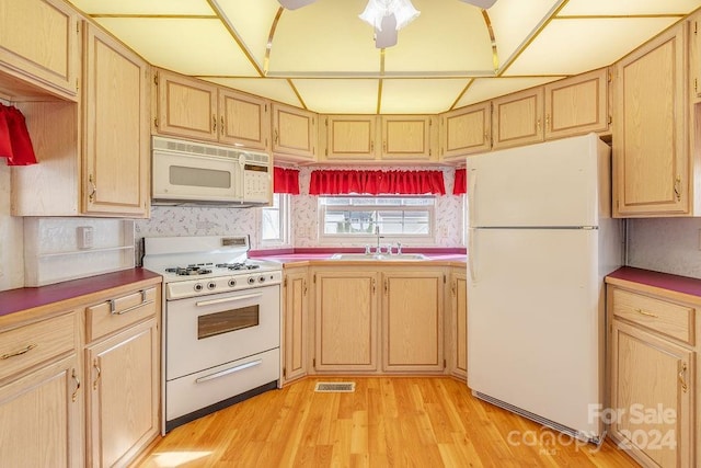 kitchen with light brown cabinetry, sink, and white appliances