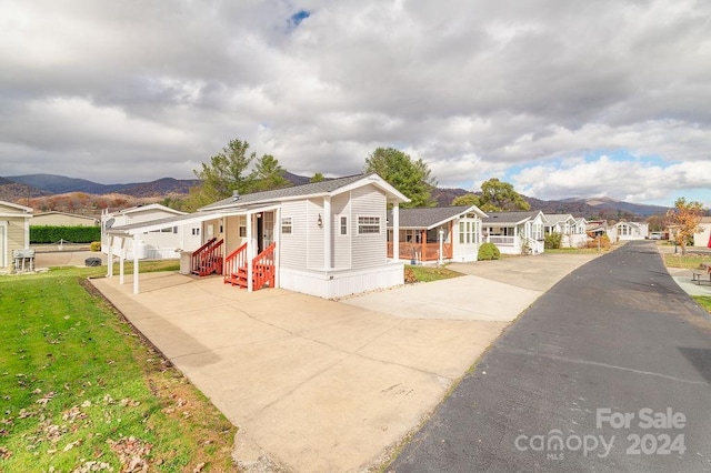 view of front of property with a mountain view, a porch, and a front lawn