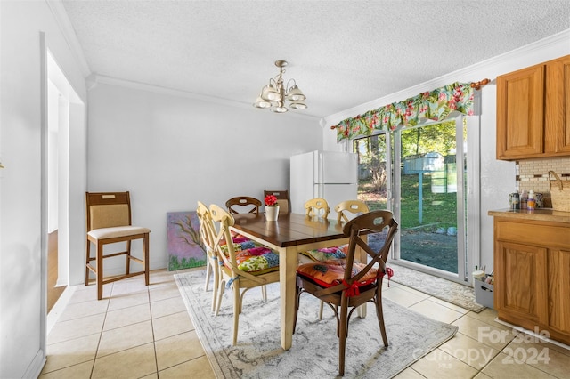 dining room featuring light tile patterned floors, a textured ceiling, ornamental molding, and an inviting chandelier