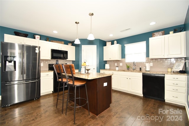 kitchen featuring a center island, black appliances, dark wood-type flooring, and pendant lighting