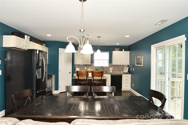 kitchen featuring black dishwasher, decorative light fixtures, a healthy amount of sunlight, and refrigerator with ice dispenser