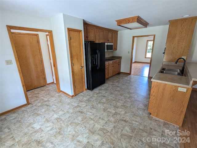 kitchen featuring black fridge with ice dispenser, gas stovetop, and sink