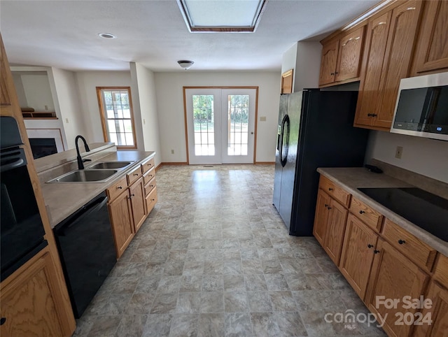 kitchen featuring black appliances, a skylight, and sink