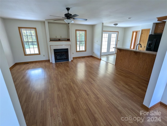 unfurnished living room featuring plenty of natural light, light hardwood / wood-style floors, and ceiling fan