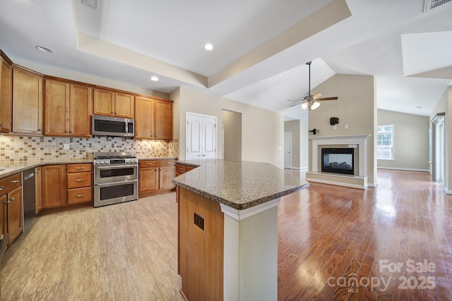 4919 Polo Gate Blvd, Charlotte, NC 28216 - kitchen with appliances with stainless steel finishes, brown cabinetry, dark stone countertops, ceiling fan, and lofted ceiling