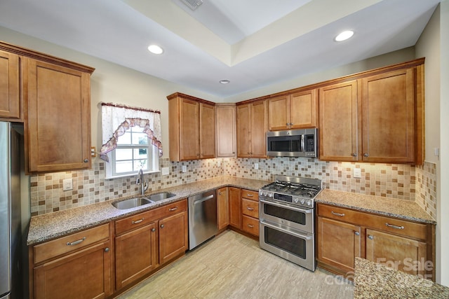 4919 Polo Gate Blvd, Charlotte, NC 28216 - kitchen with stainless steel appliances, a sink, light stone countertops, brown cabinetry, and recessed lighting