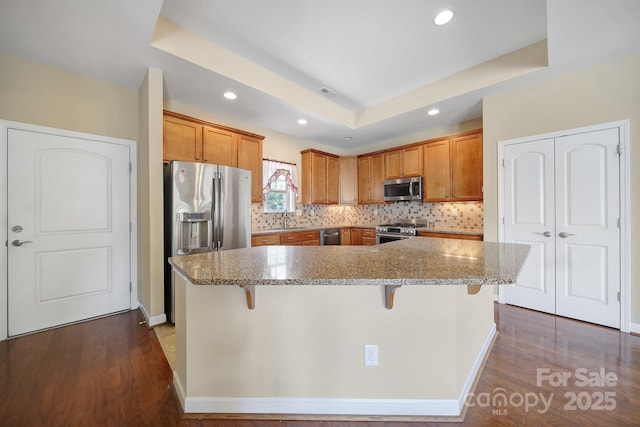 4919 Polo Gate Blvd, Charlotte, NC 28216 - kitchen featuring stainless steel appliances, recessed lighting, a kitchen bar, tasteful backsplash, and brown cabinets