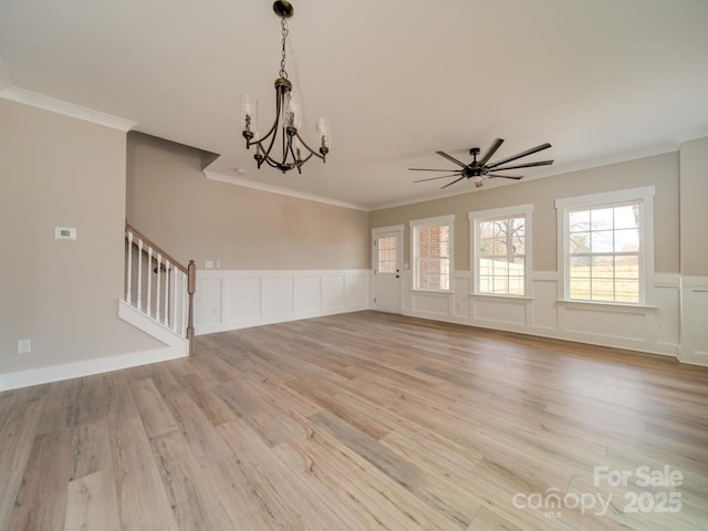 unfurnished living room featuring light wood-type flooring, crown molding, and ceiling fan with notable chandelier