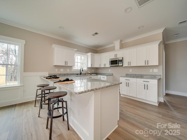 kitchen featuring white cabinetry, ornamental molding, and light stone counters